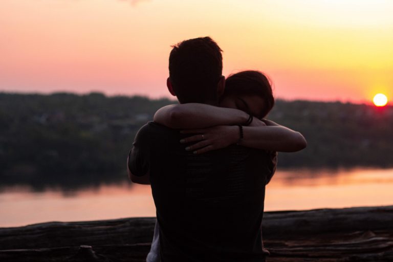 couple hugging looking into sunset