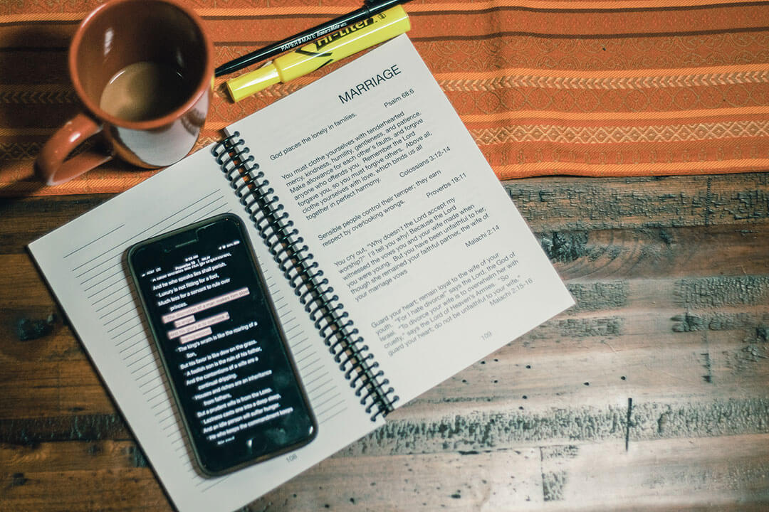 phone on top of marriage with coffee cup and pen and highlighter on table workbook